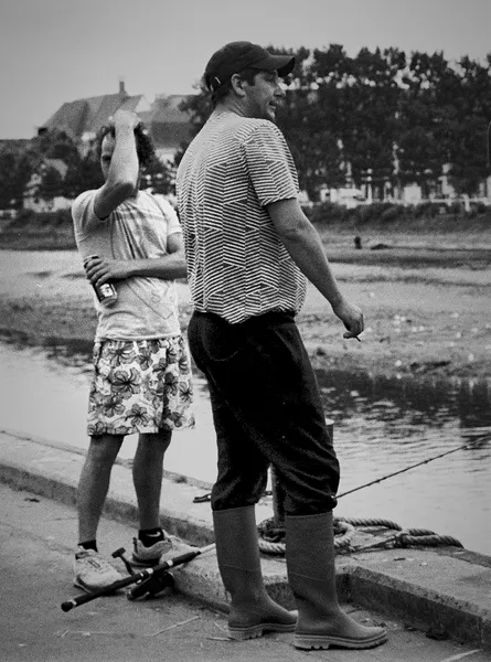 Two companions stand side by side on a quayside in Trouville-sur-mer, a timeless portrait of friendship by the water