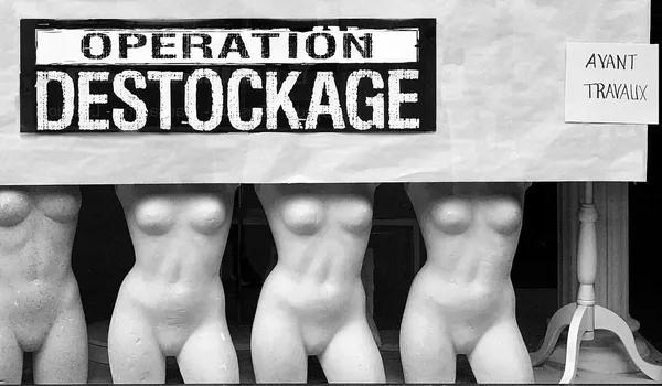 Headless mannequin torsos lined up beneath a bold clearance sale sign, a darkly humorous commentary on consumerism in Sète