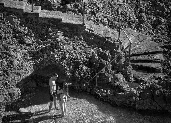 A couple stands at the foot of rugged stone steps carved into the rocky coastline of Cap d'Ail, an intimate moment framed by the Mediterranean shore