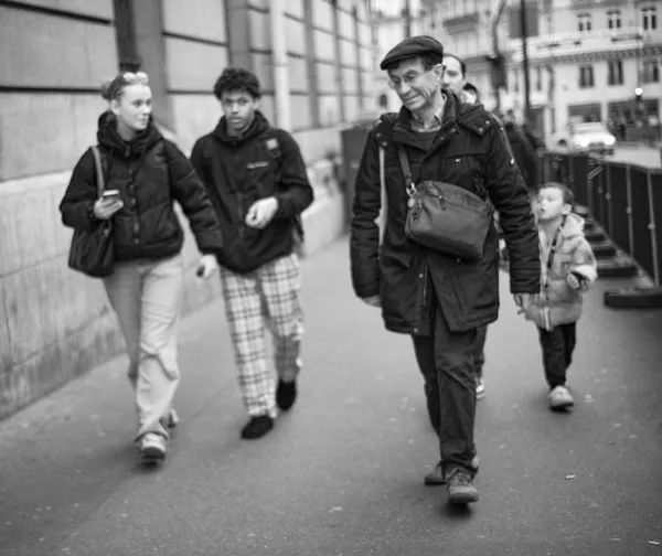 A group of strangers walks along a Parisian sidewalk, each lost in their own world, a candid street portrait of urban coexistence