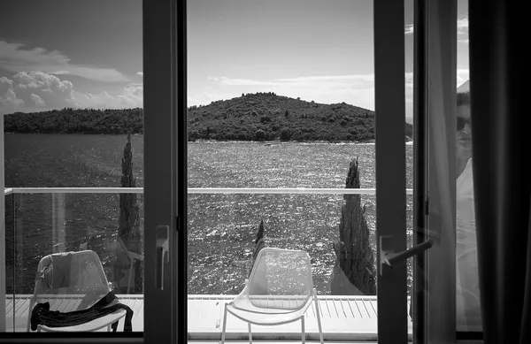 A balcony framing the Adriatic Sea and distant islands, chairs and cypress reflections composing a quiet Mediterranean tableau in Dubrovnik