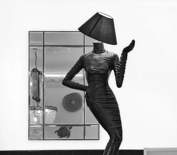 A surreal mannequin-lamp sculpture with a lampshade for a head strikes a dramatic pose before a mirror in Beaulieu-sur-mer, blurring art and interior design