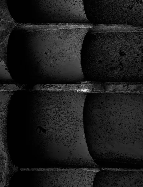 Massive concrete harbor blocks stacked in close-up, their rounded forms and rough textures resembling clenched teeth emerging from the darkness in Sète