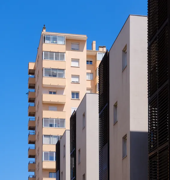 Apartment buildings in Sète stack their warm-toned facades against a bright blue sky, balconies and shutters composing a rhythmic Mediterranean color palette