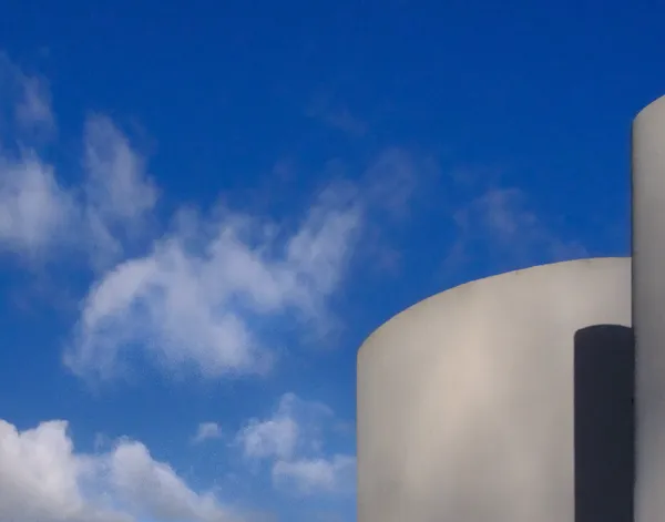 White cylindrical forms of Villa Savoye rise against a deep blue sky, minimalist modernist architecture meeting the infinite in Poissy